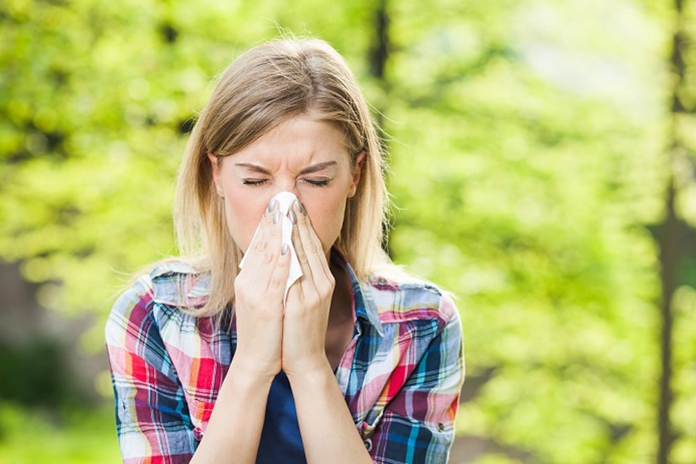 Woman with allergy symptom blowing nose